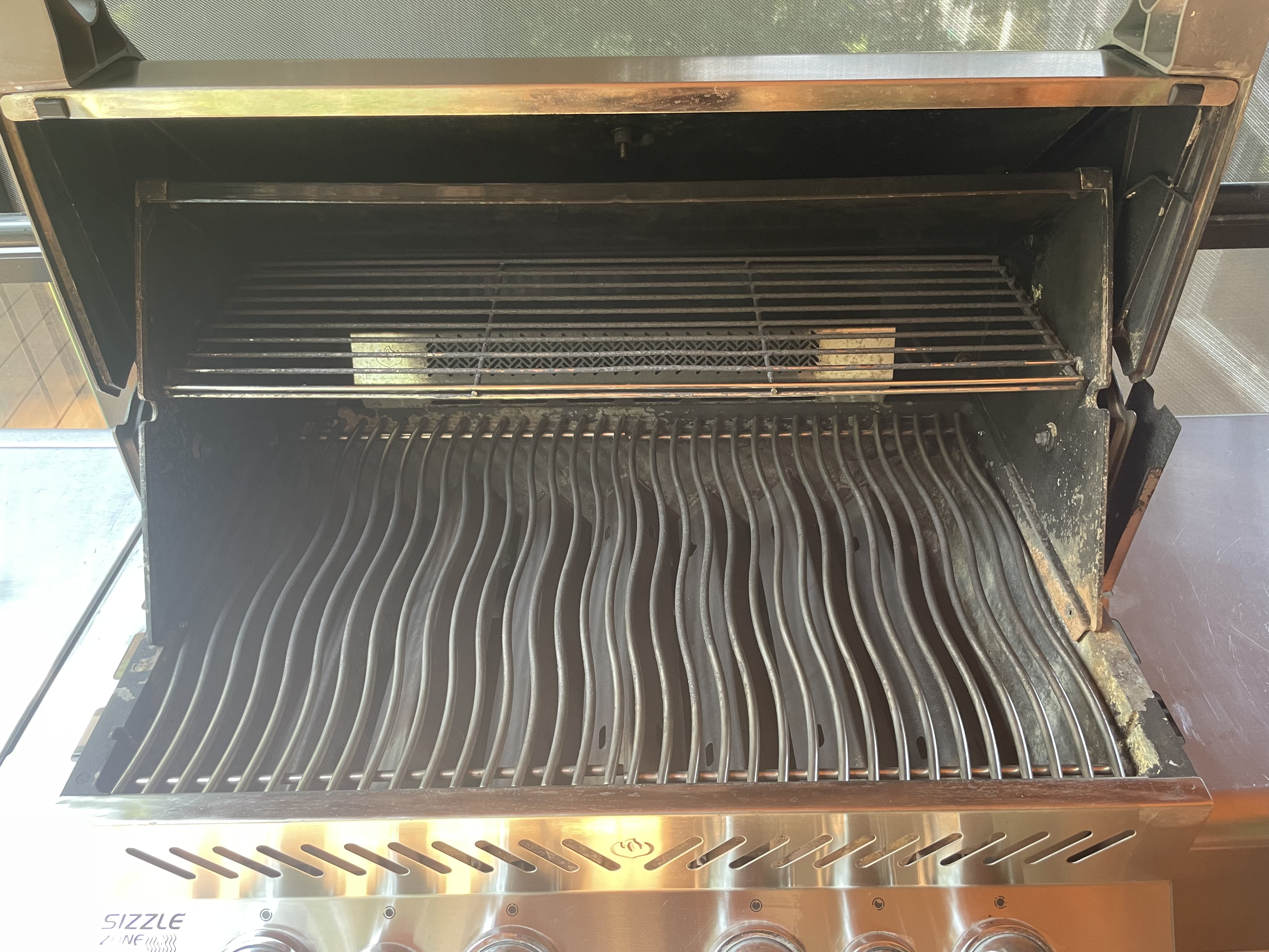 Inside that second Napoleon Prestige after an Aspect deep clean, with clean wavy cooking grates, a bright warming rack and a bare stainless firebox