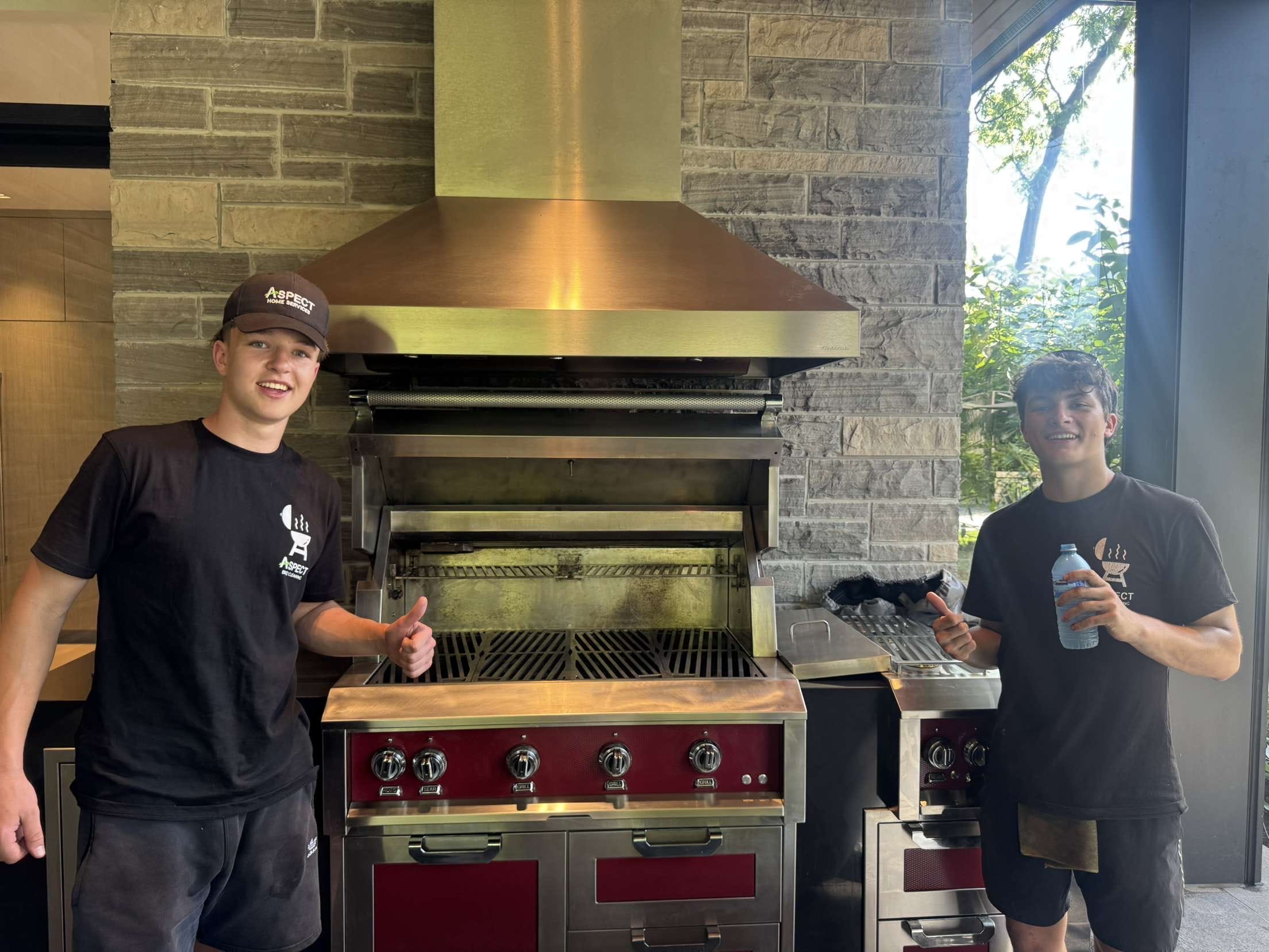 Two Aspect crew members with a freshly cleaned built-in grill